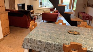 A cozy living room with a dining table, red sofas, and a staircase. - Chalet, fireplace or stove, tv, 62m², Pralognan-la-Vanoise (Pralognan-la-Vanoise)