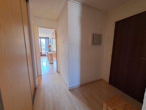 Een gang met een houten vloer die leidt naar een kamer met een donkere deur.