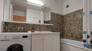 A compact bathroom with a washing machine, a sink, and a shower area. - 50m from resort center, 3rd floor, view mountain, balcony, tv, 52m², Les 2 Alpes (Les Deux Alpes)