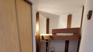 A compact bedroom with a bunk bed, a wooden wardrobe, and a small desk with a chair. - 50m from resort center, 3rd floor, view mountain, balcony, tv, 52m², Les 2 Alpes (Les Deux Alpes)