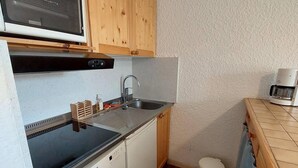 A compact kitchen with wooden cabinets, a Bosch dishwasher, a sink, and a microwave. - 50m from resort center, 3rd floor, view mountain, balcony, tv, 52m², Les 2 Alpes (Les Deux Alpes)