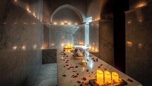A marble-tiled corridor with candles and rose petals, leading to an arched doorway. - RIAD MALIDA  (Marrakech)