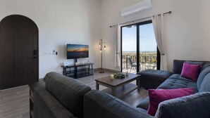Un salon moderne doté d’un grand téléviseur, d’un balcon avec vue et d’un coin salon confortable.
