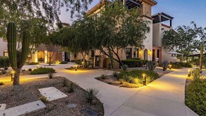 Une cour bien éclairée, avec un chemin, des cactus et un bâtiment au design moderne.