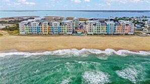 Un hotel frente a la playa con varios edificios coloridos, una playa de arena y el océano.