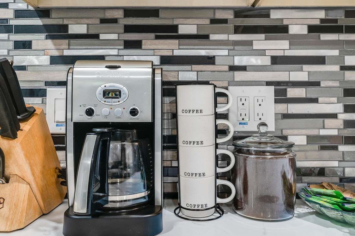 Une machine à café, une tasse à café et une cafetière sur un plan de travail de cuisine.