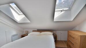 A bedroom with a skylight, a bed, a wooden dresser, and a nightstand. - Le Refuge, Chamonix Centre (Chamonix-Mont-Blanc)