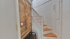 A staircase with wooden steps and white walls, a metal bench, and a wooden wall with a decorative pattern. - Le Refuge, Chamonix Centre (Chamonix-Mont-Blanc)