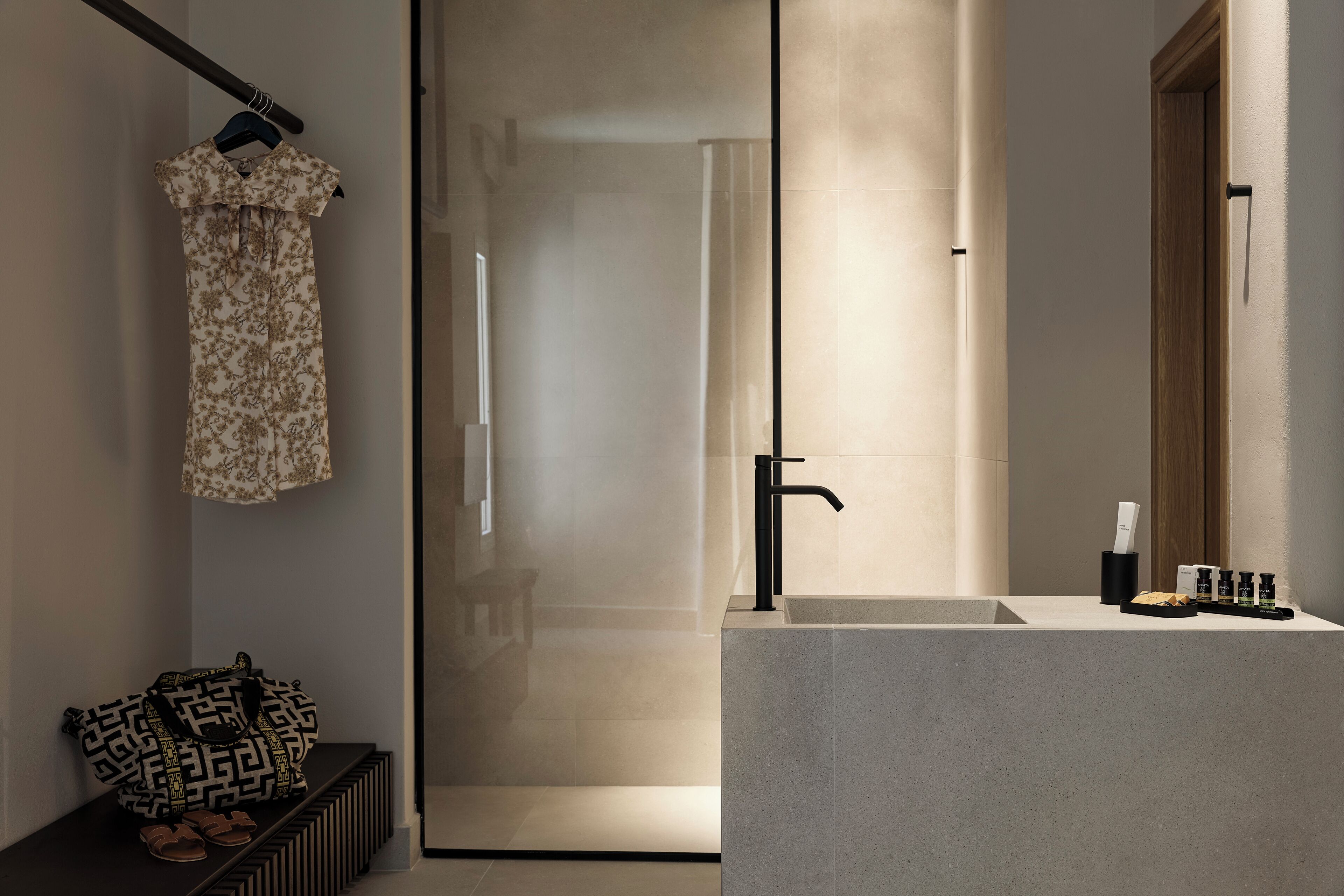 Ein modernes Badezimmer mit Duschkabine aus Glas, einem schlichten Waschbecken und einem Kleiderhaken.