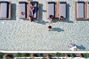 An aerial view of a pool area with lounge chairs and a person swimming. - Naxian Rhapsody (Naxos)