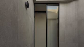Une salle de bain moderne dotée d’une lucarne, d’une douche en verre et d’une baignoire aux reflets verdâtres.