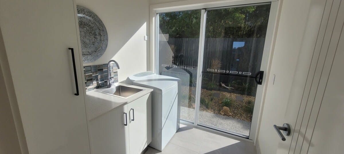 A kitchen with a sink, cabinets, and a sliding glass door leading to a patio.