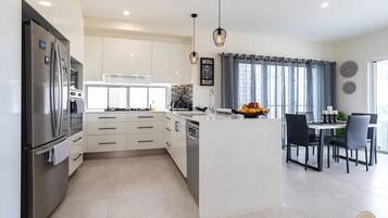 A modern kitchen with white cabinets, a central island, and a dining area with chairs.