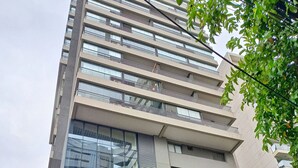 A modern high-rise building with multiple floors, large glass windows, and balconies. - Elegance Suítes Vergueiro (São Paulo)