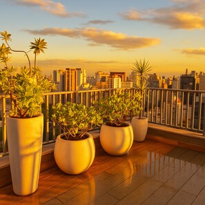 A balcony with large potted plants and a cityscape view. - Elegance Suítes Vergueiro (São Paulo)