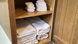 A wooden cabinet with multiple shelves holding neatly folded towels. - Newly Remodeled home with Class A Trout Stream (Austin)