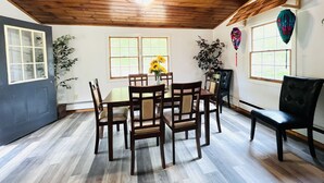 A dining area with a wooden ceiling, a table with chairs, and a vase of sunflowers. - Newly Remodeled home with Class A Trout Stream (Austin)