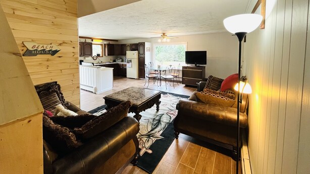A spacious living room with a high ceiling, a fireplace, and a view into the kitchen area. - Newly Remodeled home with Class A Trout Stream (Austin)