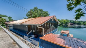 Eine am Wasser gelegene Holzhütte mit einer Holzterrasse und einer Veranda.