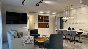 Un salon moderne comprenant un canapé, un fauteuil, une table basse et un coin repas avec des chaises et une table.