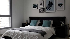 Ein Schlafzimmer mit einem großen Bett, zwei Nachttischen, einem Spiegel und gerahmten Bildern an der Wand.