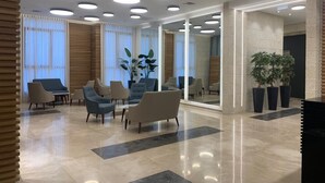 Eine moderne Lobby mit Sitzgelegenheiten, großen Fenstern und einer Pflanze.