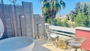 A patio with a large round table, wicker chairs, and a red wall. - The Red Farm Relais & Spa (Iklin)
