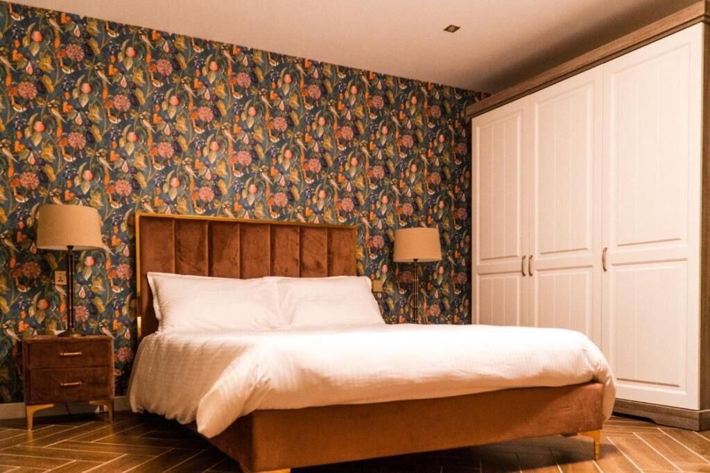 A bedroom with a bed, nightstands, and a wardrobe.