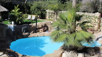 Una piscina techada, una piscina al aire libre, sombrillas