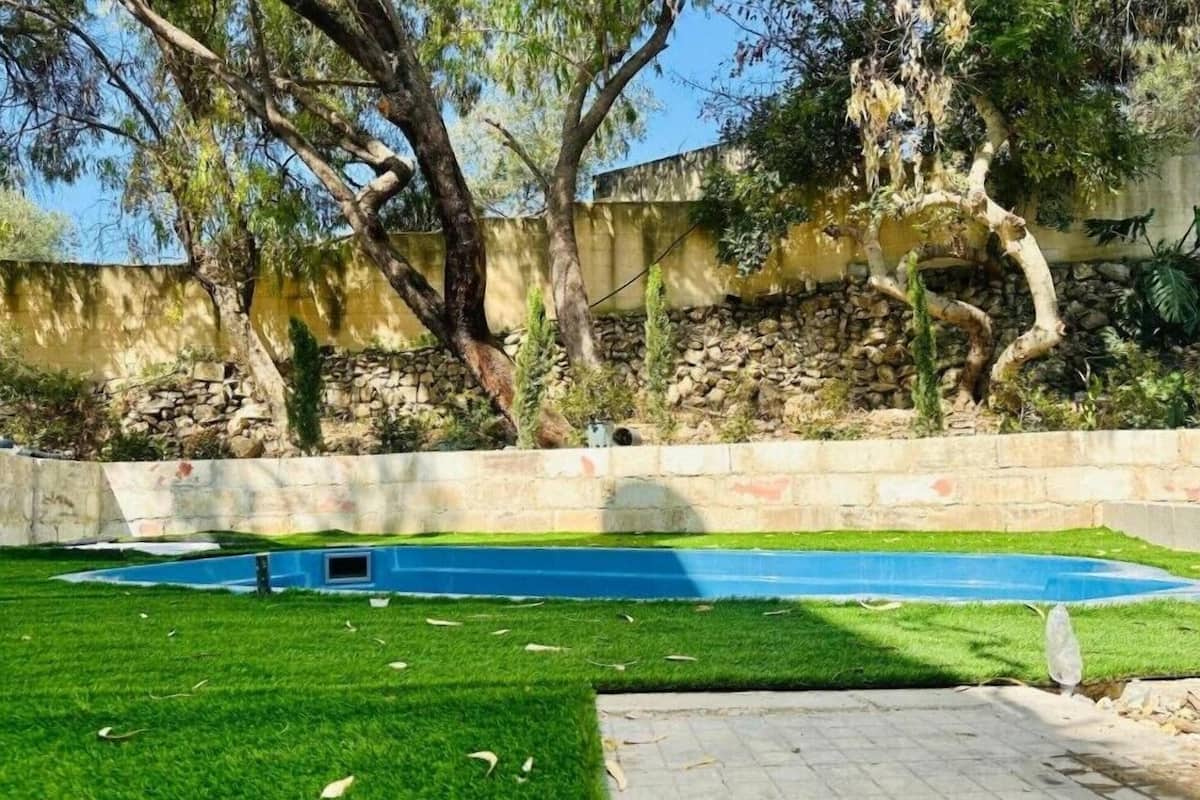 A swimming pool with a stone wall and trees in the background.