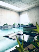 Una piscina techada, una piscina al aire libre, sombrillas