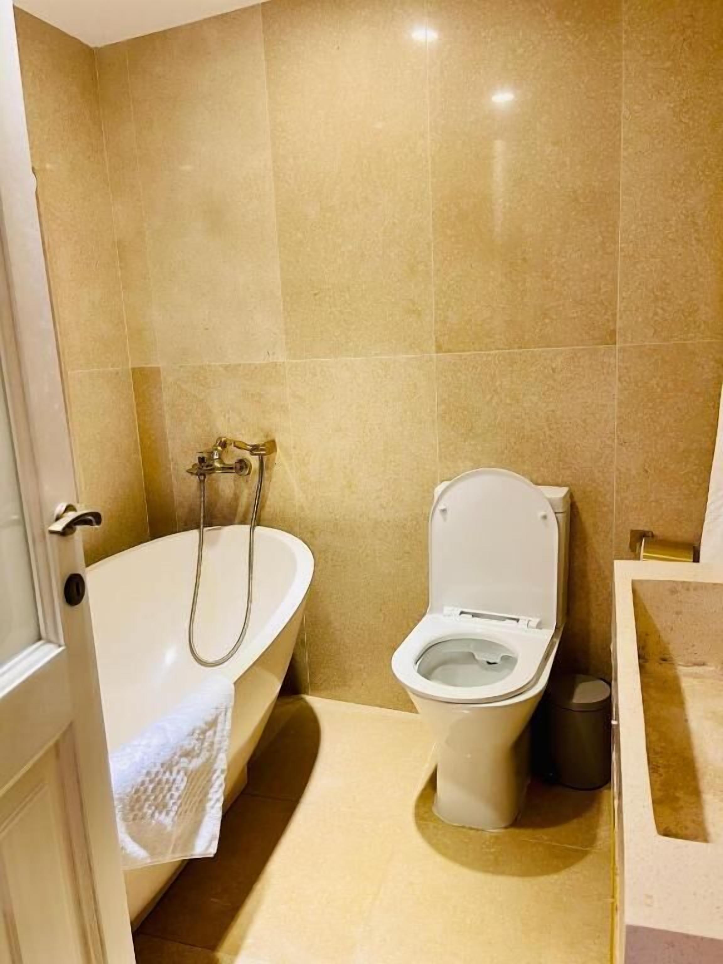 Une salle de bain avec une baignoire, des toilettes et une poubelle.