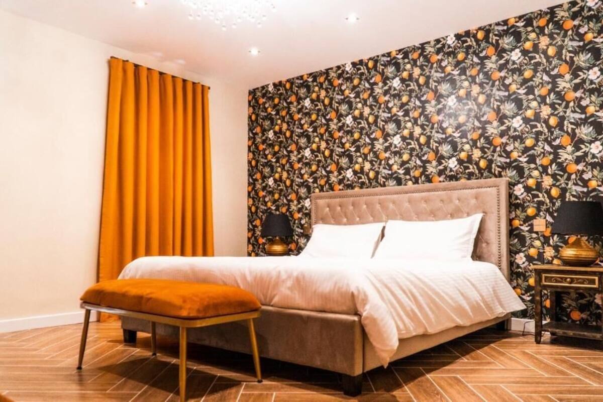 A bedroom with a bed, a bench, and a nightstand with lamps.