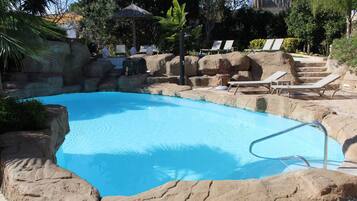 Una piscina techada, una piscina al aire libre, sombrillas