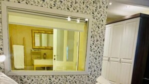 A hotel room with a large bed, a mirror, a wardrobe, and a bathroom visible through the window. - The Red Farm Relais & Spa (Iklin)