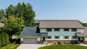 A two-story house with a garage, a front porch, and a well-maintained lawn.