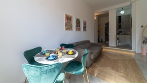 A modern dining area with a round table, teal chairs, and a grey sofa in the background. - Design Apartment - Central Station (Milano)