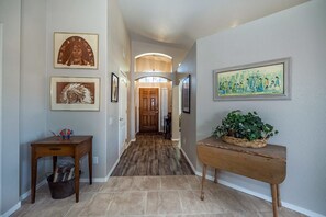 A hallway with framed artwork, a wooden bench, and a potted plant.