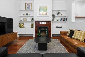 A modern living room with a fireplace, a black coffee table, a leather sofa, and a TV on a wooden cabinet.
