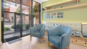 A modern room with a sofa, two armchairs, a sliding glass door, and a wall with colorful artwork. - Serenity in the City - 1BD Studio, Wifi, CBD (Adelaide)