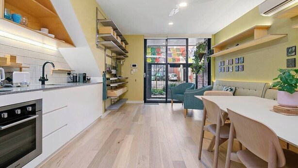 A modern kitchen with a built-in oven, a dining area with a table and chairs, and a view through a glass door to the outside. - Serenity in the City - 1BD Studio, Wifi, CBD (Adelaide)