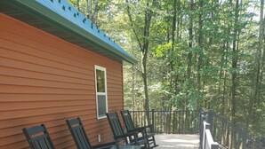 A wooden deck with outdoor seating and a view of a forested area.