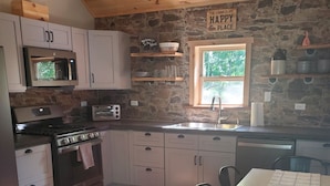 A kitchen with wooden cabinets, a stone wall, a window, and a table with chairs.