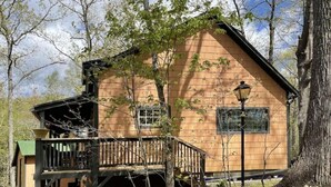 A wooden cabin with a balcony, surrounded by trees. - The Pottery Cabin (Leicester)