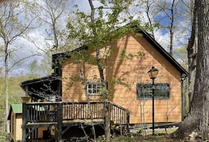 Situated among the trees, this cabin-style building features a gabled roof and a balcony with a railing.
