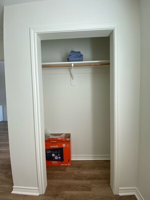 A compact closet with a shelf and a door, featuring a smart TV for entertainment.