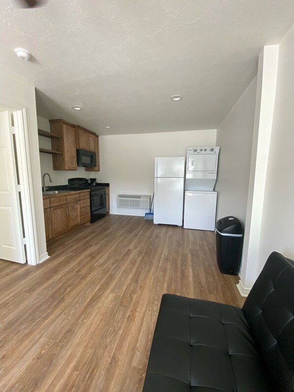 Cozy living space with a kitchenette, featuring a sofa, microwave, stove, and refrigerator.