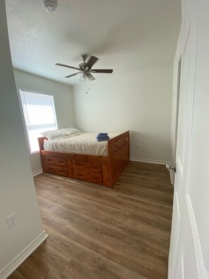 Cozy bedroom with a comfortable bed, ceiling fan, and natural light pouring in through the window.