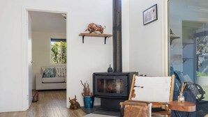 A cozy living room with a wood-burning stove, a sofa, a chair, and a small table. - Bellemarie - An Unforgettable Farm Stay (Bellthorpe)