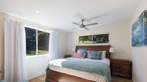 A bedroom with a bed, nightstands, a ceiling fan, a window with curtains, and a painting on the wall. - Bellemarie - An Unforgettable Farm Stay (Bellthorpe)